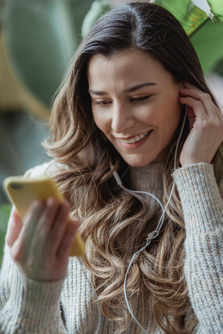smiling woman in earphones using smartphone